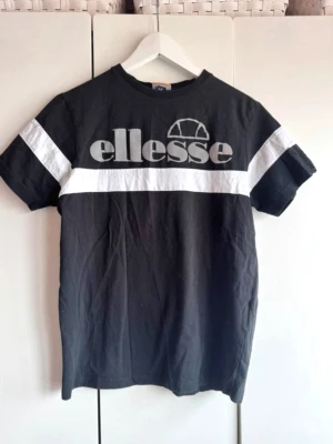 Svart och vit t-shirt från Ellesse - Svart o vit t-shirt från Ellesse. Stor logga i grått - reflex. Storlek S. Snygg men har några små prickar i reflex texten.  Syns inte mycket. Fint skick. 