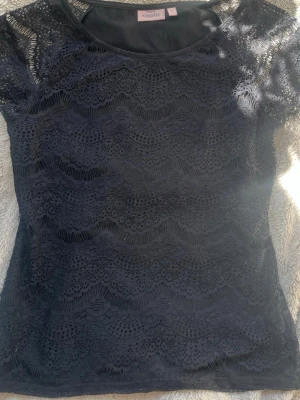 Svart spetsblus - En jättevacker spets t-shirt från KappAhl. Är i jätte fint skick och har inga syn på defekter då jag knappt kunna använda då den är för liten. Är i storlek S men passar också XS. 
