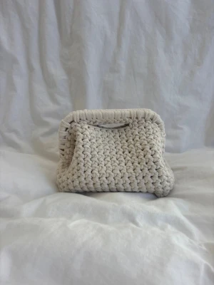 Handcrafted white clutch - Unique handcrafted crocheted clutch with 80% recycled cotton. The bag is sturdy and has a chunky texture in a rectangular/oval shape with rounded edges. The clutch is spacious while still a perfect smaller size perfect for everyday use.