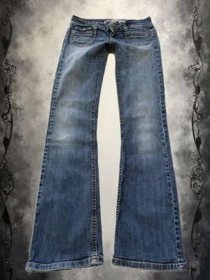 Blå bootcut jeans från only - Säljer ett par blå bootcut jeans från only med låg midja. Jeansen har fem fickor, dragkedja och knapp framtill samt tydliga sömmar. Perfekta för en avslappnad och trendig look.