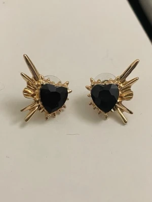 Maria Nilsdotter liknande örhängen i guld - Unika örhängen med Maria Nilsdotter style. Aldrig använda och perfekt skick.  Guldiga statement-örhängen med svart sten.   Snygga guldiga trendiga örhängen med svart sten i mitten. Trendig design som lyfter vilken outfit som helst - perfekta till fest, middagar eller när man vill sticka ut lite extra.  Statement design Lätta att bära Säljs som par