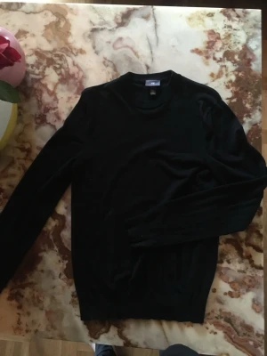 Svart slim fit stickad tröja H&M - Snygg svart stickad tröja från H&M i slim fit-modell. Tröjan har rund halsringning och långa ärmar, perfekt för lager på lager eller som den är. Enkel och stilren design som passar till det mesta.