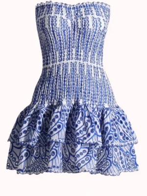 Blåvit kortklänning med volanger - Supersöt kortklänning i blått och vitt med smockad överdel och dubbla volanglager i kjolen. Klänningen är axelbandslös och har ett unikt mönster som ger en fräsch sommarkänsla. Perfekt för dig som vill ha en somrig klänning till ett event eller skolavslutning. Den är använd en gång!