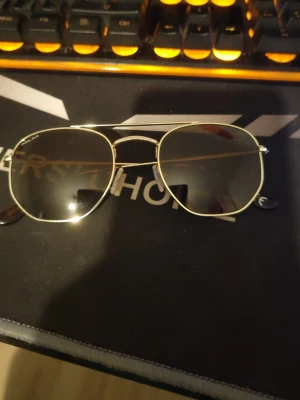 Guldiga aviator solglasögon från Polar - Snygga aviator solglasögon från Polar med guldfärgad metallbåge och mörka glas. Klassisk pilotform som ger en cool och tidlös look. Perfekta för soliga dagar och passar till de flesta outfits.