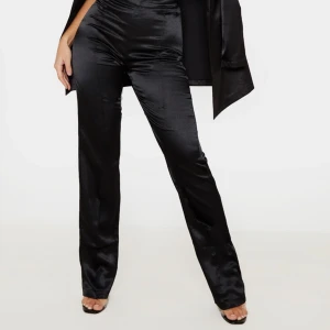 Svarta blanka satinbyxor / byxor i satin. Strlk: 25 i midjan. Felfria - Svarta blanka satinbyxor / byxor i satin. Strlk: 25 i midjan. Från Gina Tricot. Material: Kraftigare satintyg. Stängs med dragkedja och knapp. Har fickor. Felfria. Första bilden är ett exempel på liknande modell och passform.