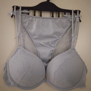 HELT NYTT, OANVÄNT set, BH + trosa. Pushup. Ljusblå, dimblå. 75A. Trosa 34-36. - HELT NYTT OCH ANVÄNT set med pushup BH + trosa med spets baktill. BH 75A, med spetsdetaljer och tunna axelband. Mjuk och glansig yta med romantiska spetspartier framtill och på sidorna. Trosa 34-36. För dig som gillar en feminin och trendig look. Felfritt. Se bilder för egen bedömning.