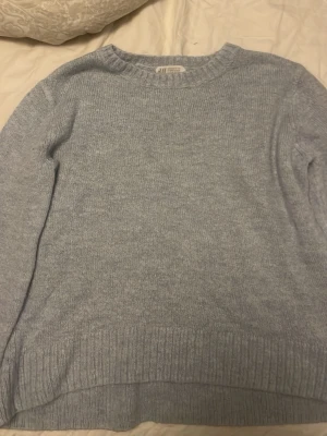 Ljusblå stickad tröja från H&M - Mysig ljusblå stickad tröja från H&M med rund halsringning och ribbade muddar vid ärmslut och nederkant. Perfekt för lager på lager och enkel att matcha med jeans eller kjol. Klassisk och stilren modell som passar till många olika looks.