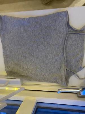 Grått linne från H&M - Säljer en enkel och stilren grått linne från H&M. Toppen är ärmlös med smala axelband och har en mjuk, stretchig känsla i bomullsmix. Perfekt att matcha med jeans eller kjol för en avslappnad look. Storlek 146-152 .