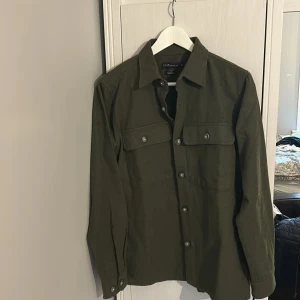 grön overshirt - En stilren overshirts i militärgrönt. Materialet är mjukt och känns som bomull, perfekt nu. Passar dig som är 180-185. Storlek S, skriv om ni har något fundering. 220kr