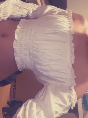 Vit offshoulder croppad topp - Trendig vit offshoulder topp med croppad passform och långa puffiga ärmar. Smockad över bröstet för en snygg och bekväm look. Perfekt till höga jeans eller kjol för en cool stil.