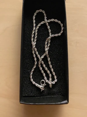 ropechain halsband 50cm - Snyggt halsband i silverfärg med tvinnad kedja som ger en stilren och modern look. Halsbandet har ett klassiskt lås och passar perfekt till olika stilar. Levereras i svart ask.