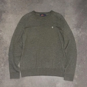 Grön tröja från Morris - Säljer en stilren grön tröja från Morris i 100% merinoull. Tröjan har en liten broderad detalj på bröstet och ribbade muddar vid ärmslut och nederkant. Perfekt för kyligare dagar! Inga defekter och är i 10/10 skick. Tröjan är i L barnstorlek vilket motsvarar xs i herrstorlek.