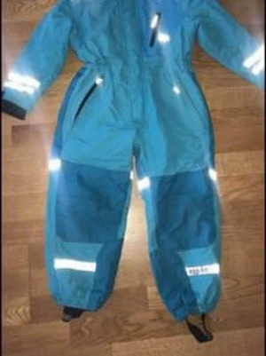 Blå täckbyxor med reflexdetaljer - Säljer ett par blå täckbyxor med praktiska reflexdetaljer på benen och ärmarna. Byxorna har dragkedja framtill, elastiska benslut och justerbara fotband. Perfekta för kalla dagar och utomhusaktiviteter. Materialet är slitstarkt och vattenavvisande.