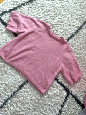 Rosa stickad tröja från 157 - Mysig rosa stickad tröja från 157 med rund halsringning och ribbade kanter. Tröjan har en avslappnad passform och kortare ärmar, perfekt för lager på lager. Materialet känns mjukt och bekvämt mot huden. OBS! på bild 2 å 4 kan ni se små detaljer som visar att den är använd, det är små detaljer som inte syns så mycket, kan också lagas 