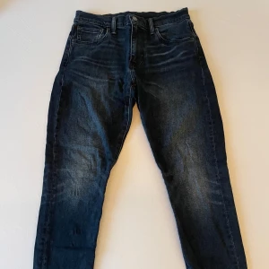 Mörkblå Levi's jeans straight fit - Säljer ett par mörkblå jeans från Levi's med klassisk femficksmodell och raka ben. Jeansen har snygga slitningar och kontrastsömmar, samt en brun läderpatch bak i midjan. Perfekta till en avslappnad stil och passar till det mesta.