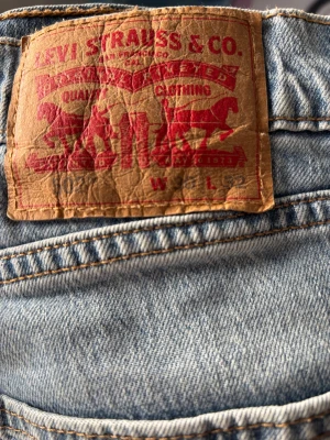 Levi's ljusblå jeans med klassisk patch - Säljer ett par ikoniska ljusblå jeans från Levi's med den klassiska bruna patchen bak i midjan. Jeansen har en tidlös passform och är tillverkade i slitstarkt denimtyg. Perfekta för dig som gillar en avslappnad och trendig stil. Jag tror att helt nya kostar runt 700-800kr. Så bra kvalité 