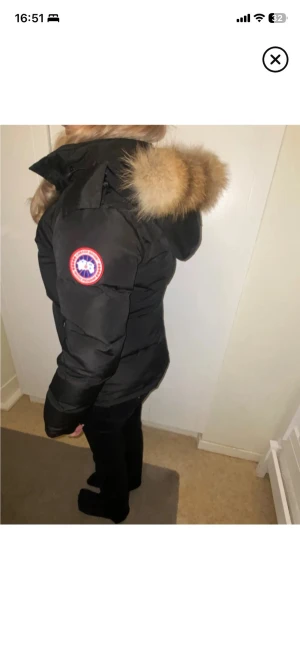 Svart canada - Säljer en svart dunjacka från Canada Goose med avtagbar luva och stor pälskant. Jackan har en klassisk patch på ärmen, dragkedja framtill och två stora fickor. Perfekt för kalla vinterdagar och riktigt varm. Jackan är oanvändbar och har band inuti som man kan dra till för en mer snatched look , jackan är i storlek L men liten i storlek då den hade passat nån med storlek s-m