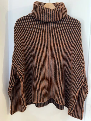 Stickad  polotröja  - Säljer en oversized grovribbad svart brun  polotröja. Tröjan har hög polokrage och vida ärmar för en avslappnad look. Ullblandad material som är båda mjuk och tjock.