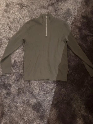 Olivgrön halvzip tröja only&sons - Säljer en olivgrön långärmad tröja med halvzip och hög krage. Tröjan har en enkel och stilren design, perfekt för lager på lager. Materialet ser ut att vara mjukt och bekvämt, och muddar vid ärmsluten ger en snygg passform.