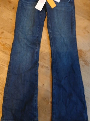 Blå bootcut jeans low waist - Säljer ett par blå bootcut jeans med låg midja, modell 'scandi low waist bootcut jeans'. Klassisk femficksdesign och snygg passform som ger en retrovibe. Perfekta för dig som gillar en avslappnad men trendig stil.