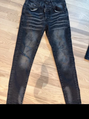 Dsquared2 jeans - Snygga svarta skinny jeans med slitningar och blekta detaljer. Jeansen har fem fickor, dragkedjegylf och coola färgstänk för en trendig look. Perfekta för dig som gillar streetstyle och vill sticka ut lite extra.
