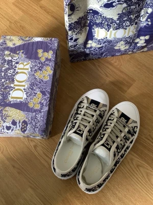 Dior Oblique låga sneakers - Snygga Dior Oblique sneakers i canvas med det ikoniska blå och vita mönstret. Klassisk låg modell med vita snören och tåparti i gummi. Märkeslogga på plösen och sidorna. Perfekta för dig som vill sticka ut med exklusiv streetstyle.