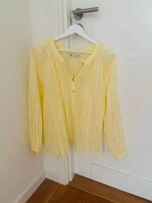 Blus - Oversized gul blus från Zara med v-ringning och knappar framtill. Blusen har långa ärmar och är tillverkad i ett lätt material som ger en avslappnad känsla. Perfekt för dig som gillar en enkel men stilren look.