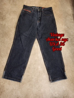 Vintage Aem'kei NYC jeans - USA size 36!! Model IKE/00 These stylish jeans are perfect for the y2k resurgence!  It features a button fly, double belt loops, large pockets, several accent details, and a sturdy construction. The colour is is a dark grey with hints of blue. Overall these jeans are in very good condition, except fraying on the bottom backside of the jeans. Size W36 USA converts to roughly 2XL EU. Please check a size guide before purchasing. Check other ads for bundle discount information 