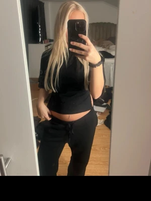 Svart croppad omlottopp med knyt - Svart croppad topp med kort ärm och snygg knytning i ryggen. Toppen har en omlott-design som ger en trendig look och passar perfekt till både jeans och kjol. Enkel och stilren modell som är lätt att matcha.