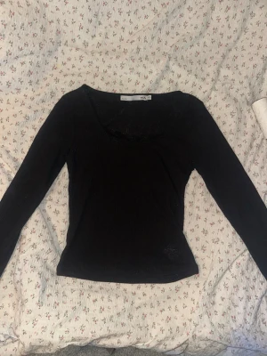 Svart ribbad topp med spets från 157 - Svart långärmad topp från 157 med ribbad struktur och fin spetsdetalj vid ringningen. Snygg och enkel modell som passar till mycket.