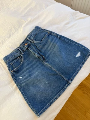 Blå denimkjol med slitningar - Säljer denna blå denim kjol från Hm, aldrig använd utan bara legat i garderoben och skräpat. Säljer den för 100kr och är i super bra skick. 