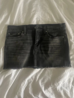 Svart jeanskjol från Levi's - Snygg svart jeanskjol från Lewis. Kjolen har en kort passform och är tillverkad i denim med en cool, tvättad look. Perfekt att styla med en t-shirt eller hoodie för en avslappnad vibe. Aldrig andvänd.