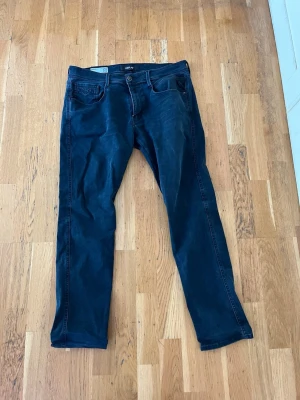 Mörkblå slim fit jeans från Replay - Snygga mörkblå jeans från Replay, modell Anbass, med slim fit passform. Jeansen har klassisk femficksdesign och är tillverkade i Hyperflex-material för extra stretch och komfort. Perfekta för en trendig och avslappnad look.