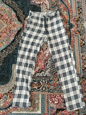 Rutiga pyjamasbyxor i bomull - Säljer ett par klassiska pyjamasbyxor med blåvitt rutmönster och dragsko i midjan. Byxorna är raka i modellen och gjorda i mjuk bomull, perfekta för chill hemma eller sovstunden. Använd bara en gång. 