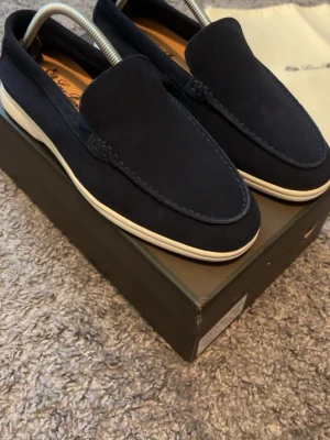 Mörkblå loafers från LP - Stilrena mörkblå loafers från LP i mocka med vit sula. Klassisk design med rundad tå och diskreta sömmar. Perfekta för en avslappnad men snygg look. Skorna har en mjuk insida och är lätta att ta på. Säljer för att de inte passade mig…😎