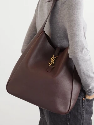 Bordeaux axelväska från Saint Laurent - Snygg bordeaux axelväska från Saint Laurent i slätt läder med ikoniskt YSL-emblem i guld framtill. Väskan har en stilren, rymlig design med bred axelrem och minimalistisk form. Perfekt för dig som gillar lyxiga accessoarer med klassisk touch.