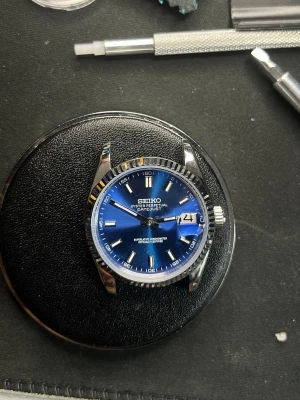 Seiko blå klocka Oyster Perpetual - Snygg Seiko Oyster Perpetual Datejust-inspirerad klocka med blå urtavla och silverfärgade index. Boetten är i blankt stål och urtavlan har datumfönster vid klockan tre. Klassisk rund form och stilren design som sticker ut med sin blå färg. HELA KLOCKAN INGÅR 