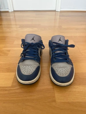 Nike Air Jordan 1 Low sneakers - Storlek 40,5 - Säljer ett par Air Jordan 1 Low i blå/ljusgrå färgkombination. Skorna är i bra skick med normalt slitage från användning och fortfarande väldigt fräscha. Bekväma och stilrena sneakers som passar både till vardags och streetwear. Storlek 40.5.