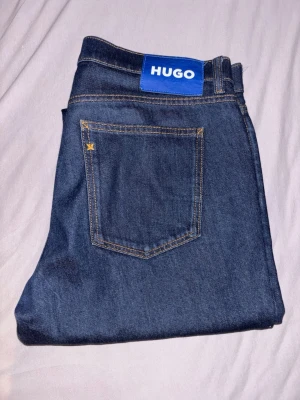 Mörkblå jeans från Hugo boss - Snygga mörkblå jeans från Hugo Boss med klassisk femficksdesign och raka ben. Nypris: 2000 kr, säljs för 1000 kr. Endast använda en gång och i mycket fint skick.