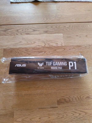 ASUS TUF Gaming P1 musmatta - ASUS TUF Gaming P1 är en svart, rektangulär musmatta designad för gaming. Den har TUF Gaming-logga och är tillverkad i slitstarkt material som ger bra precision och kontroll för musrörelser. Perfekt för dig som vill ha en snygg och funktionell musmatta till datorn. Måtten på mattan är 260x360 mm. Den är helt oöppnad så är garanterat ny!
