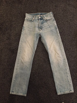Ljusblå raka jeans i vintage-stil - Säljer ett par ljusblå jeans med raka ben och klassisk femficksdesign. Jeansen har en snygg tvättad look och hög midja. Perfekta för dig som gillar en avslappnad och tidlös stil. Materialet är 100% bomull.