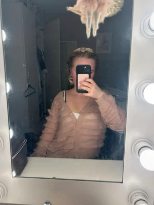 Rosa fluffig kofta från Zara - Supersöt rosa kofta från Zara med fluffiga vågiga detaljer över hela plagget. Koftan har v-ringning, knäppning framtill och långa ärmar. Perfekt för dig som vill ha en mysig och trendig look med lite extra attityd.