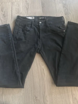 Svarta jeans från Replay - Snygga svarta jeans från Replay med modellen Hyperflex, jeansen är i fint skick och har en storlek på 29x32