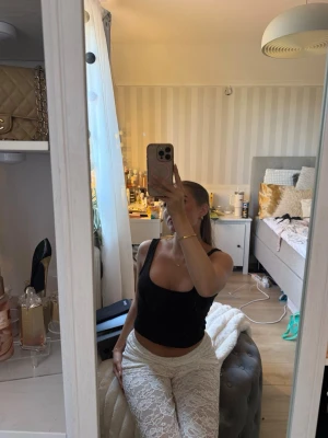 Svart ribbad linnetopp  - Svart ribbad linnetopp med breda axelband och rundad halsringning. Toppen är ärmlös och har en tight passform som framhäver figuren. Perfekt att matcha med jeans eller kjol för en trendig look.