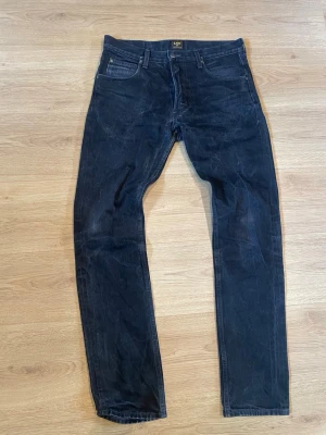 Svarta slim fit jeans från Lee - Säljer ett par svarta slim fit jeans från Lee med klassisk femficksdesign. Jeansen har en diskret tvättad look och Lee-logga på bakfickan. Perfekta för dig som gillar en tidlös stil.                           Bara att höra av dig vid frågor om tex mått.                  Pris kan diskuteras vid snabb affär