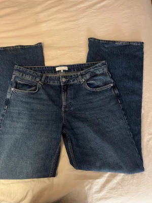 Nakd mörkblåa vida jeans med låg midja  - Säljer ett par mörkblå jeans vida jeans med låg midja. Jeansen är köpta för en vecka sedan från Nakd och är enbart använda en gång pga för stor storlek. I övrigt har jeansen låg midja och är tillverkade i kraftigt denimtyg. Dem är köpta för 699kr, men säljer för 450kr. (Observera priset kan diskuteras!)   Jeansens mått är följande:  Innerbenslängd: 83cm. Midjemått (rakt över): 44cm.   Hör av dig vid frågor och funderingar! 