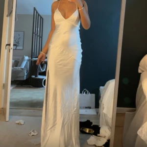 Bal klänning  - Supersnygg vit långklänning med smala axelband, v-ringning och öppen rygg. Endast använd 1 gång. KOMMER INTE SÄNKA PRIS KÖPTE FÖR 700kr!