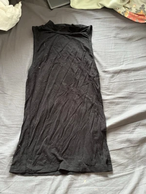 Svart ärmlös polotopp - En enkel och stilren svart polotopp utan ärmar. Toppen har en hög krage och är gjord i mjukt bomullsmaterial, perfekt att matcha med jeans eller kjol för en clean look. Passar S/Xs