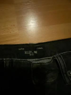 Svarta jeans från Replay - Säljer ett par svarta jeans från Replay med klassisk femficksdesign och raka ben. Jeansen har en stilren look och är tillverkade i denim. Perfekta för dig som gillar en enkel och tidlös stil.