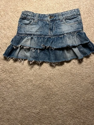 Volangkjol i jeans från Gina Tricot - En blå jeanskjol med volanger från Gina Tricot. Jättefin men tyvärr för liten för mig, därför säljer jag den!